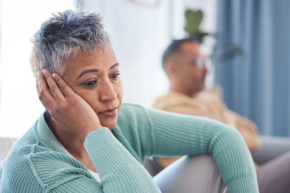 A woman sitting alone looking sad and withdrawn during the menopause transition